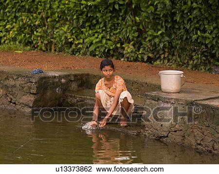 Stock Image - Girl washing in river water. Fotosearch