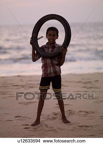 Picture - Indian boy holding a circular tube. Fotosearch
