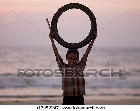 Stock Photo - Indian boy holding a circular tube. Fotosearch