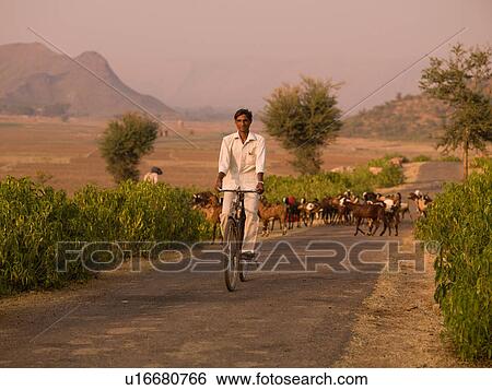 Stock Photograph - Indian man riding a bike on rural road. Fotosearch