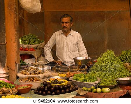 Picture - Man behind table of food in India. Fotosearch
