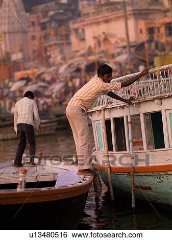 Man on boat holding onto another boat in India View Large Photo Image Stock Photograph - Man on boat holding onto another boat in India. Fotosearch