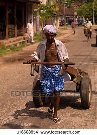Picture - Man pulling two-wheel cart. Fotosearch