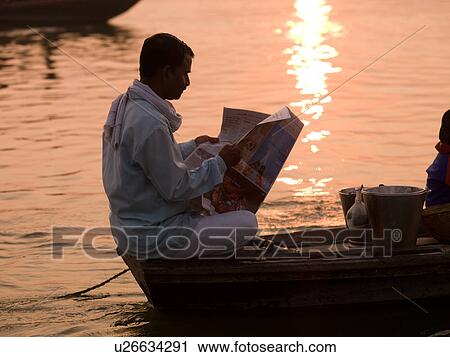 Man reading a newspaper on his boat on the Ganges River in India View Large Photo Image Stock Image - Man reading a newspaper on his boat on the Ganges River in India. Fotosearch