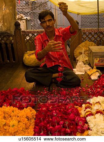 Picture - Man stringing flowers in India. Fotosearch
