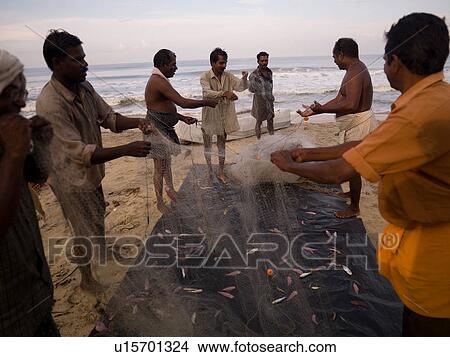 Picture - Men opening fish nets on shore of Arabian Sea. Fotosearch