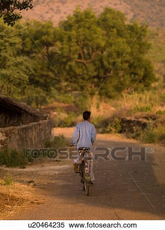 "Rajasthan, India - Man riding his bike through a field" View Large Photo Image Stock Photography - "Rajasthan, India - Man riding his bike through a field". Fotosearch