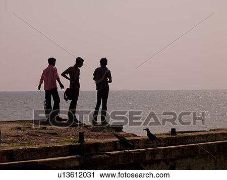 "Silhouette of three men standing at the shoreline in Alleppey, Kerala, India" View Large Photo Image Stock Image - "Silhouette of three men standing at the shoreline in Alleppey, Kerala, India". Fotosearch