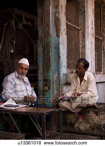 Two men sitting at corner of building View Large Photo Image Stock Photo - Two men sitting at corner of building. Fotosearch