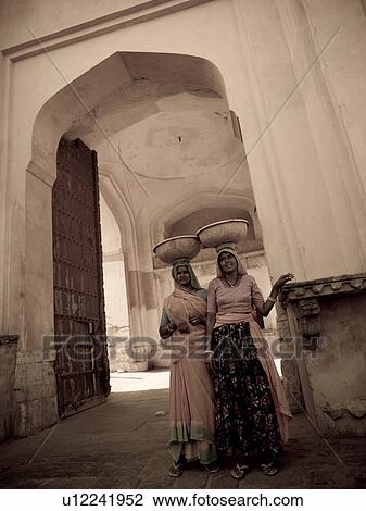 Two women balancing containers on their heads in India View Large Photo Image Stock Image - Two women balancing containers on their heads in India. Fotosearch