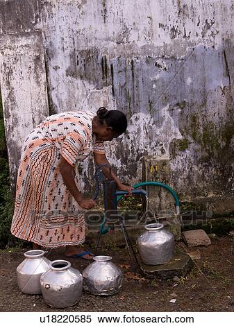 Stock Photography - Woman filling pots of water in Kerala India. Fotosearch