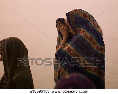 Stock Image - Women praying at the Ganges River in India. Fotosearch