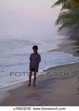 Stock Image - Young boy staning on beach in India. Fotosearch
