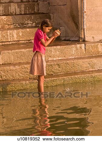 Stock Image - Young girl standing in the Ganges River in India. Fotosearch