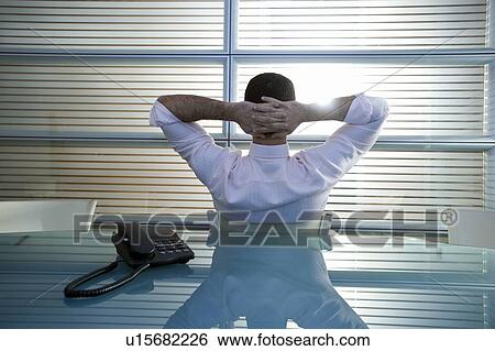 Back view of businessman in office with hands behind head View Large Photo Image Stock Photograph - Back view of businessman in office with hands behind head. Fotosearch
