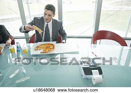 Stock Photo - Business people eating pizza at desk. Fotosearch