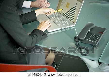Stock Image - Business people with laptop showing bar chart. Fotosearch
