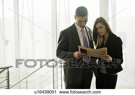 Businessman and businesswoman looking at financial newspaper View Large Photo Image Stock Image - Businessman and businesswoman looking at financial newspaper. Fotosearch