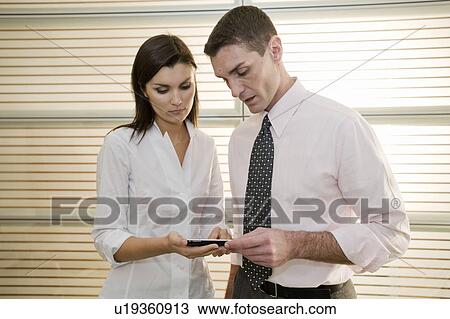 Stock Image - Businessman and businesswoman looking at calculator. Fotosearch