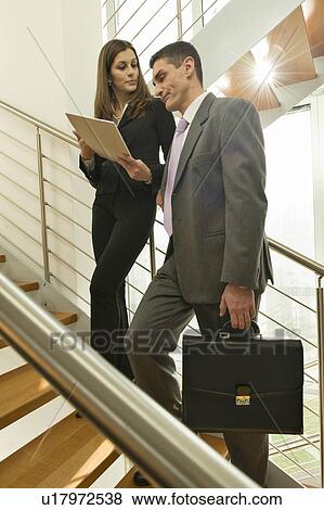 Stock Photo - Businessman and businesswoman on staircase discussing over document. Fotosearch