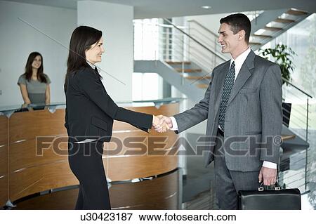 Stock Photo - Businessman and businesswoman shaking hands at reception. Fotosearch
