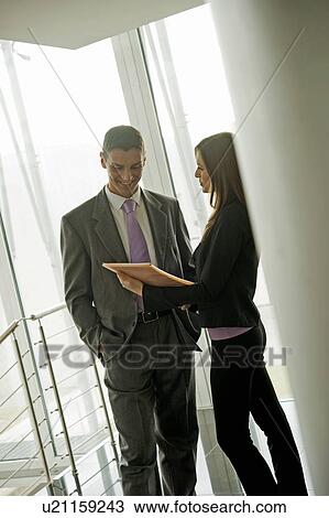 Stock Image - Businessman and businesswoman discussing over document. Fotosearch