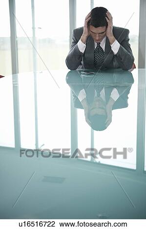 Businessman at desk holding his head View Large Photo Image Stock Image - Businessman at desk holding his head. Fotosearch