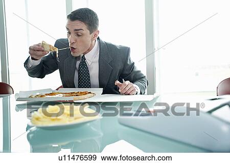 Businessman eating pizza with French fries at desk View Large Photo Image Stock Photo - Businessman eating pizza with French fries at desk. Fotosearch