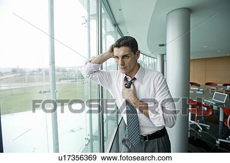 "Businessman looking out the window, adjusting tie" View Large Photo Image Stock Photo - "Businessman looking out the window, adjusting tie". Fotosearch