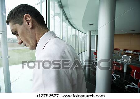 Businessman looking out window View Large Photo Image Stock Photo - Businessman looking out window. Fotosearch
