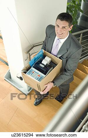 Picture - Businessman on office staircase with box of belongings. Fotosearch