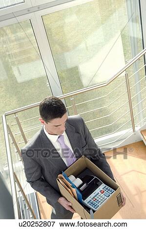 Stock Photo - Businessman on office staircase with box of belongings. Fotosearch