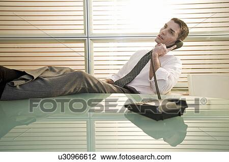 Businessman on telephone with legs up on desk View Large Photo Image Stock Image - Businessman on telephone with legs up on desk. Fotosearch