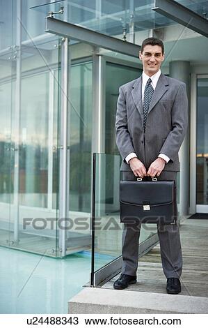 Businessman outside office building entrance View Large Photo Image Stock Image - Businessman outside office building entrance. Fotosearch