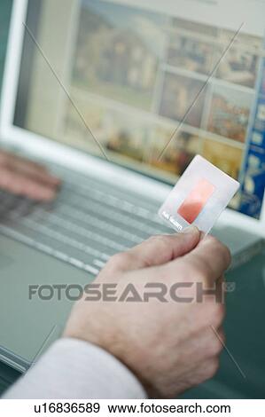 Stock Photo - Businessman's hands holding credit card at laptop. Fotosearch