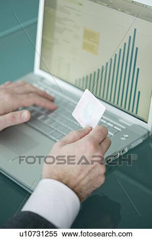 Businessman's hands holding credit card at laptop with bar chart View Large Photo Image Stock Photography - Businessman's hands holding credit card at laptop with bar chart. Fotosearch
