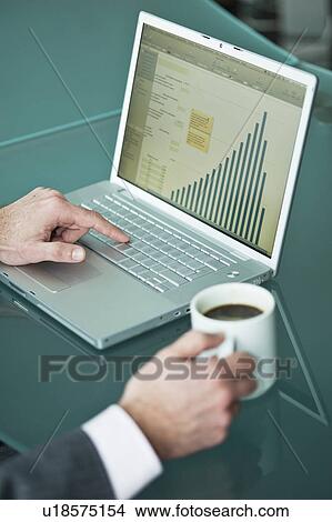 Businessman's hands with coffee cup at laptop with bar chart View Large Photo Image Picture - Businessman's hands with coffee cup at laptop with bar chart. Fotosearch