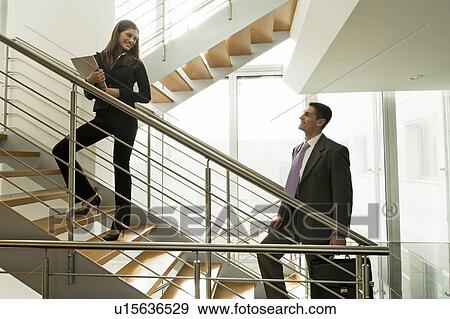 Stock Photo - Businesswoman and businessman on office staircase. Fotosearch
