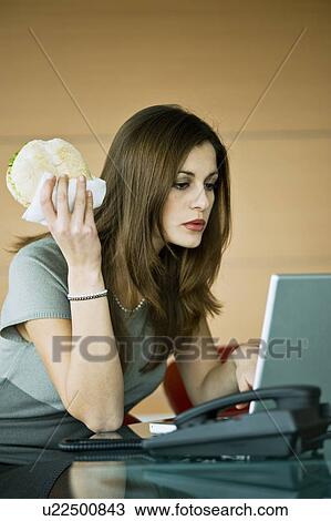 Businesswoman eating pita sandwich at laptop View Large Photo Image Stock Image - Businesswoman eating pita sandwich at laptop. Fotosearch
