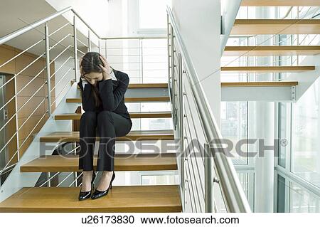 Businesswoman on office staircase holding her head View Large Photo Image Stock Image - Businesswoman on office staircase holding her head. Fotosearch