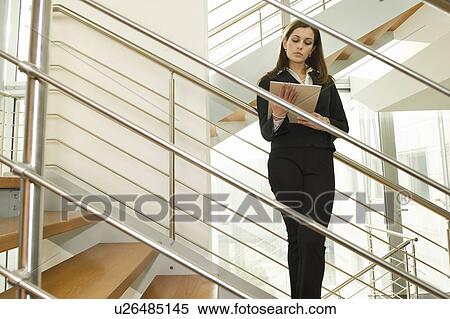 Businesswoman on staircase reading document View Large Photo Image Stock Photography - Businesswoman on staircase reading document. Fotosearch
