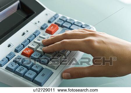 Stock Image - Closeup of woman's hand using calculator. Fotosearch