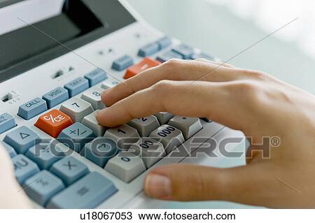Stock Image - Closeup of woman's hand using calculator. Fotosearch
