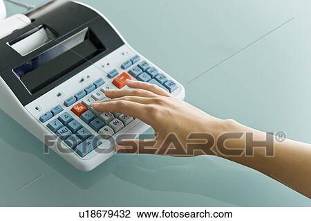 Stock Image - Closeup of woman's hand using calculator. Fotosearch