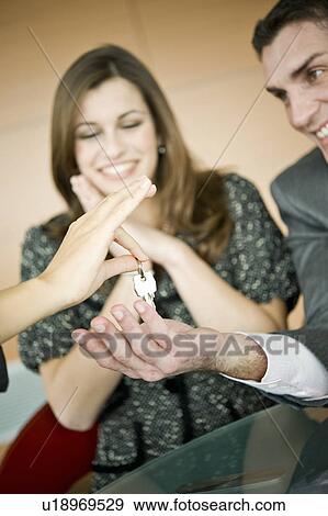 Couple receiving keys from female hand View Large Photo Image Stock Photo - Couple receiving keys from female hand. Fotosearch