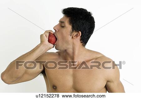 Fit young man biting an apple View Large Photo Image Stock Photo - Fit young man biting an apple. Fotosearch