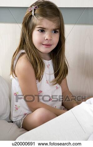 Stock Image - Girl sitting on bed. Fotosearch