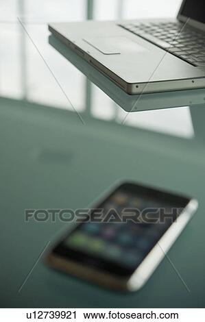 Stock Image - Laptop with cell phone on conference table. Fotosearch