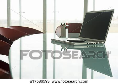 Stock Image - Laptop with cell phone on conference table. Fotosearch