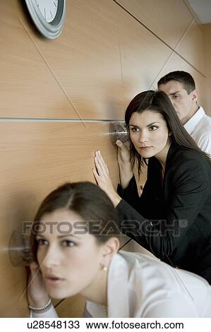 Office workers eavesdropping against wall View Large Photo Image Stock Image - Office workers eavesdropping against wall. Fotosearch